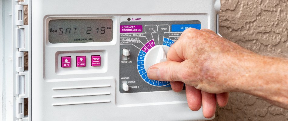 Person adjusting an irrigation controller in Cary, NC.