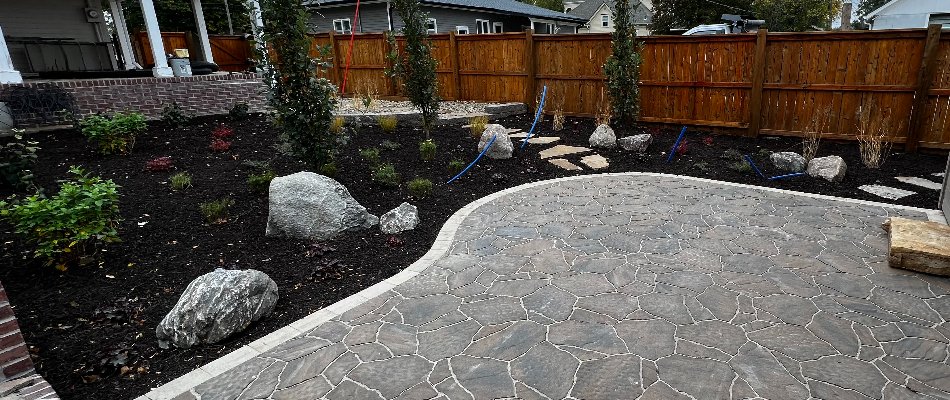 Landscape bed in Omaha, NE, with mulch, plants, and boulders.