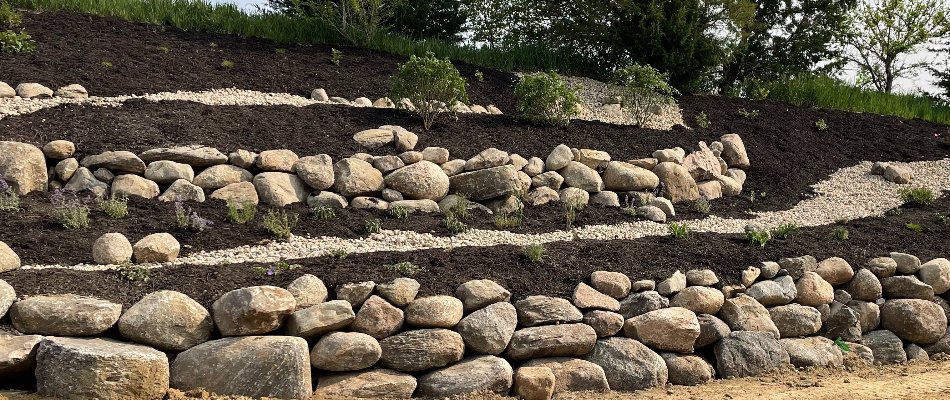 Sloped landscape in Omaha, NE, with black mulch.