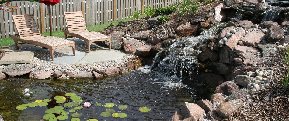Lounge chairs by a waterfall with pond in Omaha, NE.