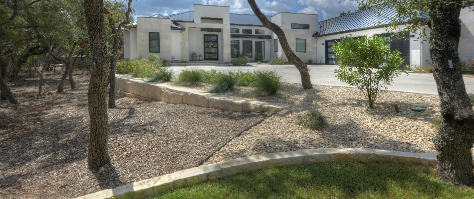 Front landscape in New Braunfels, TX, with a retaining wall and plants.