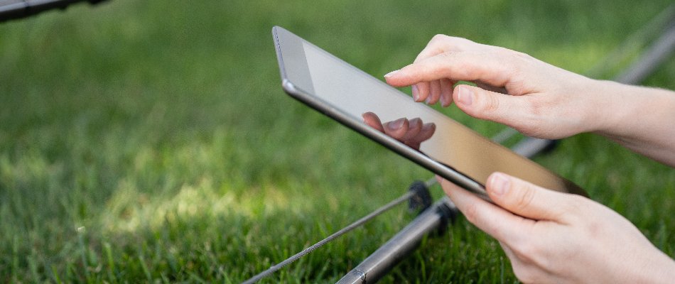 Person holding a tablet to control an irrigation system for a property in Cary, NC.