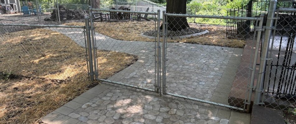 Paver walkway under chain link fence on a property in Maryville, IL.