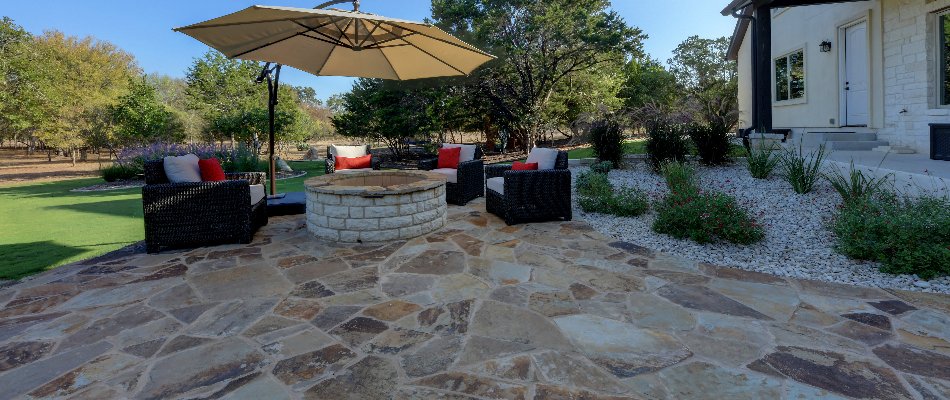 Flagstone patio in New Braunfels, TX, with a fire pit and chairs.