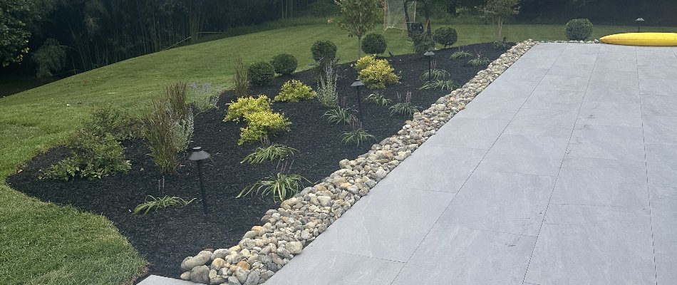 Landscape bed in Chester Springs, PA, with rocks, mulch, plants, and lighting.