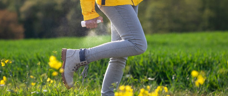 Person wearing jeans in Grand Rapids, MI, spraying insect repellent.