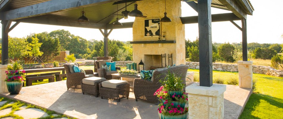 Concrete patio in New Braunfels, TX, with a fireplace and furniture.